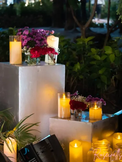 The decor included these modern silver pedestals with candles and floral arrangements, adding to the sophisticated and warm ambiance of the anniversary party.