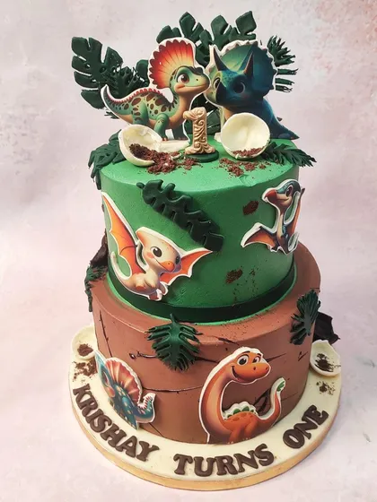 We go back in time with this adventurous two-tiered dinosaur cake. The design combines a green jungle tier with a brown, earthy tier, both decorated with various baby dinosaurs and prehistoric foliage for a one-year-old's first big adventure.