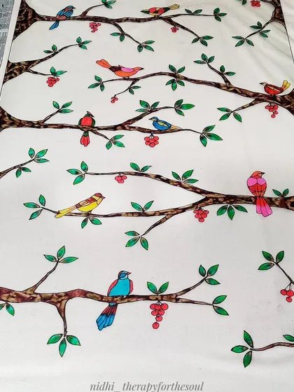 The glass painting in progress, with many of the birds and leaves filled in with color.