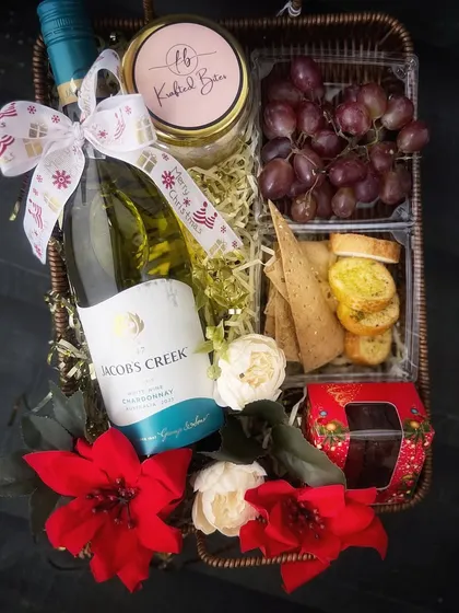 A Jacob's Creek bottle, grapes and savoury treats appear in our Christmas basket, with a jar carrying Krafted Bites branding.