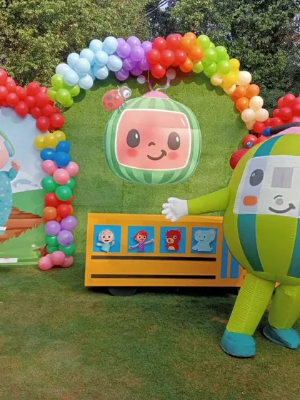 The Cocomelon bus character greets guests at an outdoor party. I can provide mascots that match your party's theme, like this one for a Cocomelon birthday celebration.
