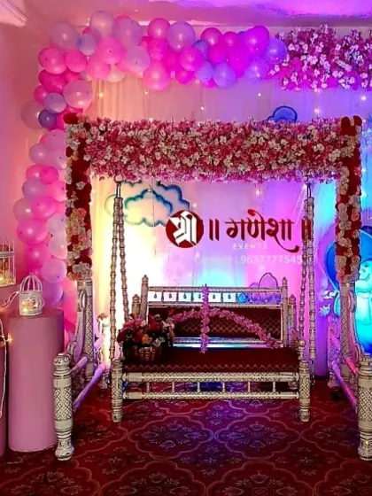 A modern and stylish baby shower decoration in pink and purple tones. This setup includes a flower-draped swing, balloon arrangements, and elegant lanterns to create a beautiful ambiance.