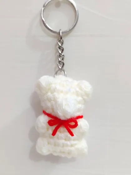 A white gummy bear keychain with a red bow.