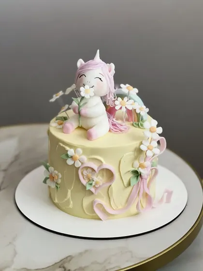 A different angle of the daisy unicorn cake, showing the delicate fondant flowers and ribbons that complete this whimsical design.