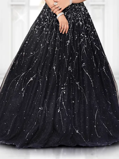 A detailed look at the flowy tulle skirt of our black reception gown, which is covered in delicate, light-catching embellishments.