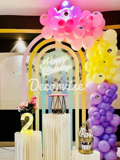 This setup demonstrates how we use color and light to create a vibrant party atmosphere. A pastel rainbow backdrop is accented with a neon "Happy Birthday" sign and a multi-colored balloon garland.
