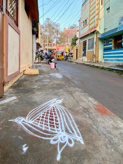A traditional kolam or rangoli drawn on the pavement. This ephemeral art form is a daily act of placemaking, transforming a simple sidewalk into a threshold of beauty and welcome.