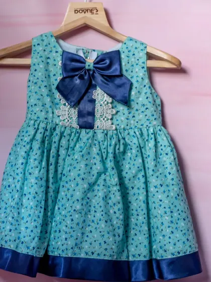 A sweet turquoise printed dress with delicate lace detail and a bold navy blue bow.