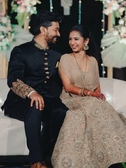 The couple sharing a happy moment, seated on a modern white sofa at their reception.