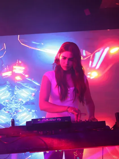Mixing tracks under a mix of red and blue lights at Ibiza, Jhansi. The colorful lighting sets the mood and enhances the energy of the music.