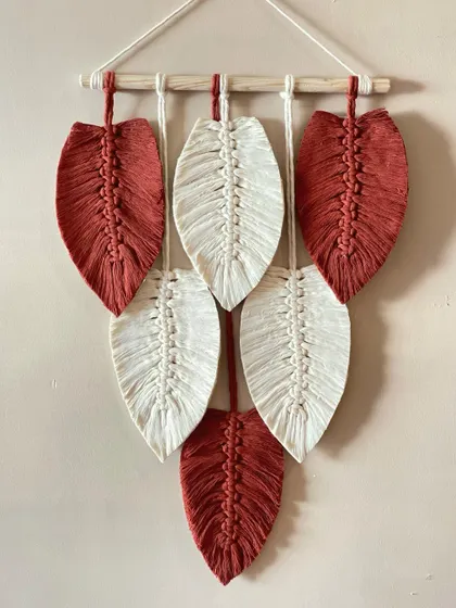 A simple yet striking wall hanging featuring alternating rust-colored and off-white macrame leaves. The color contrast makes the design pop.