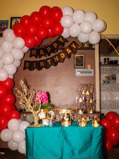 A classic and vibrant home party decoration. We used a simple gold ring frame to structure a red and white balloon arch, creating a perfect backdrop for a cake table filled with decorative props.