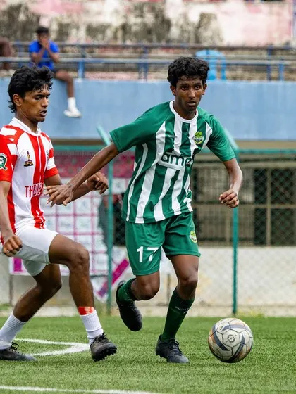 A player drives forward with the ball, looking to break through the opposition's defense during a Youth Premier League match.