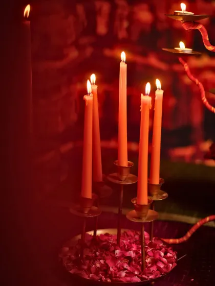 Tall orange candles in brass holders cast a warm, inviting glow, perfect for an intimate dinner.