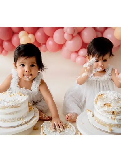 Double the fun, double the cake! A first birthday cake smash session for adorable twin girls, set against a beautiful pink balloon garland.