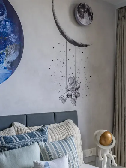 The wall art in this kids' room brings the universe indoors, with a crescent moon, a dreamy astronaut, and a unique astronaut sculpture lamp that adds playful wonder.