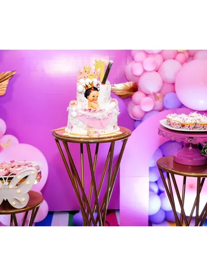 The birthday cake and cupcakes are displayed on elegant gold and pink stand's.
