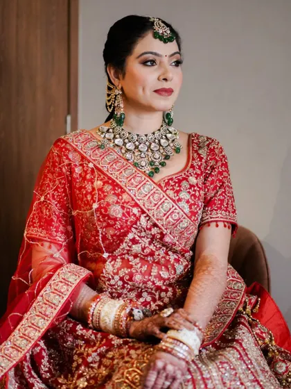 A seated portrait that captures the richness of her lehenga and the elegance of her makeup. The deep red lip and softly defined eyes are a classic combination that never fails.