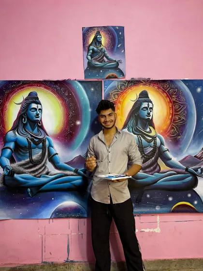 A photo of me with my brushes and palette next to the completed cosmic Shiva commissions.