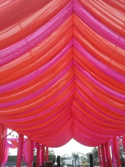This vibrant outdoor setup uses bright pink and orange drapes to create a colorful canopy. This is a simple yet effective way we create a festive atmosphere for daytime functions like Mehendi or Haldi.