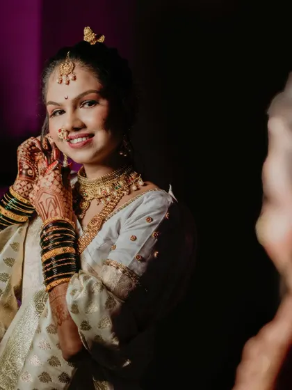 The bride adjusts her earring while looking in the mirror. This candid getting-ready shot is a beautiful way to capture the final moments of anticipation before she walks down the aisle.