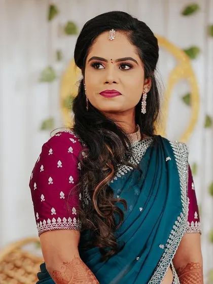 A portrait of the bride in a deep blue saree with a contrasting maroon blouse, looking elegant and poised.