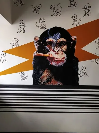 A full view of the 'Smokin Monkey' mural, set against a background of smaller, sketch-style monkeys and a bold orange lightning bolt.