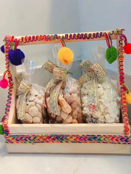 A simple yet festive Lohri hamper in a wooden tray, containing three bags of traditional treats.