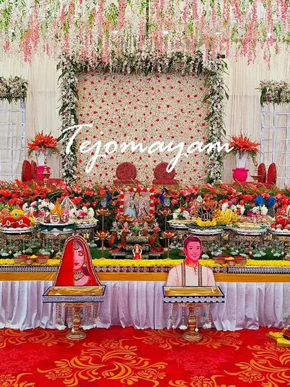 A beautiful engagement setup with a backdrop of hanging flowers and personalized caricature props for the bride and groom.
