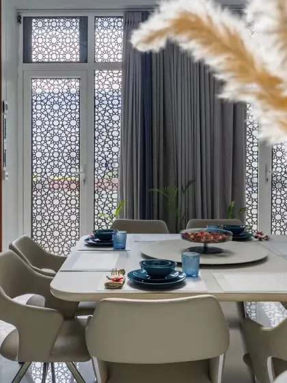 We believe dining areas should be inviting. In this space, we used intricate jali work on the windows to filter light beautifully, creating a serene ambiance around the contemporary dining set.