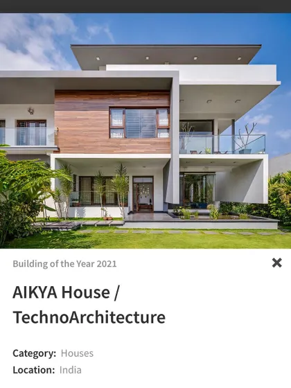 The 'AIKYA House', nominated for Building of the Year, features a clean, modern facade with cantilevered balconies and a balanced composition of wood, glass, and white walls.