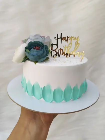 Simple yet beautiful. This cake uses a petal effect with teal buttercream and is topped with a small bouquet of artificial flowers.