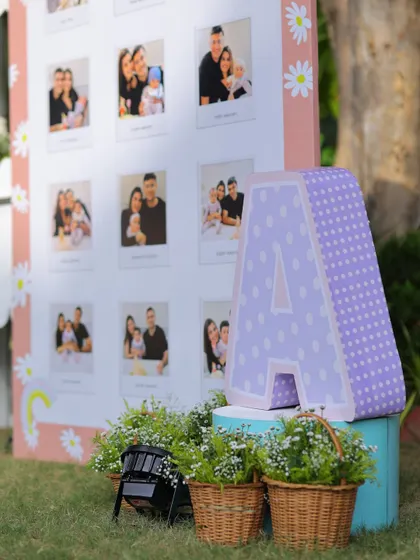 A close-up of the milestone board corner, featuring a large polka-dotted letter 'A' and baskets of fresh flowers, adding to the rustic charm of the outdoor setup.