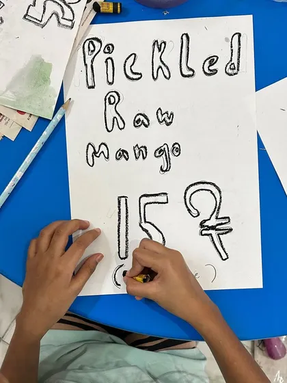 A sign for "Pickled Raw Mango" shows the variety of products our young entrepreneurs came up with for the fundraiser.