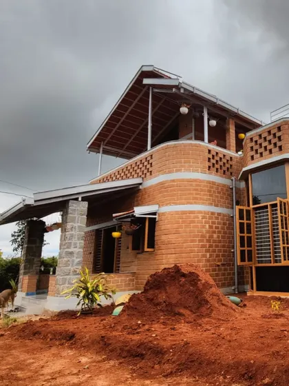 Here you can see the interplay of different materials, from the exposed brick and stone pillars to the sloped roofing. This view shows the home during the final stages of construction, surrounded by the natural landscape.