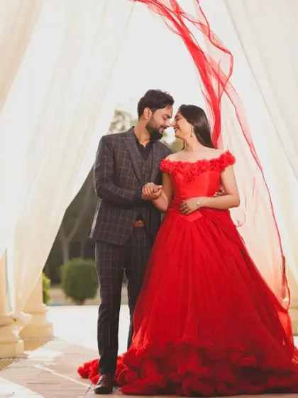 A classic pre-wedding pose. The bride to be wears our off shoulder red ball gown, which contrasts beautifully with her partner's checkered suit.