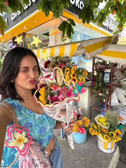 A winking selfie at a flower stall, with a floral outline to match the theme.