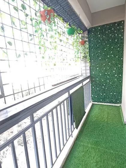 This view highlights how a green makeover can transform the feel of a small balcony. The artificial grass and vertical garden make the space look more inviting and purposeful.