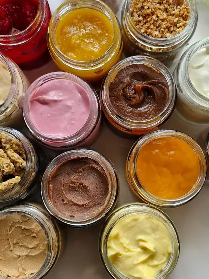 A beautiful top-down view of various fillings and frostings in jars, showcasing the variety of our masterclass.