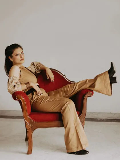 A full-length shot from the same series, showing a confident and relaxed pose. This image highlights the full outfit and the beautiful design of the vintage chair.