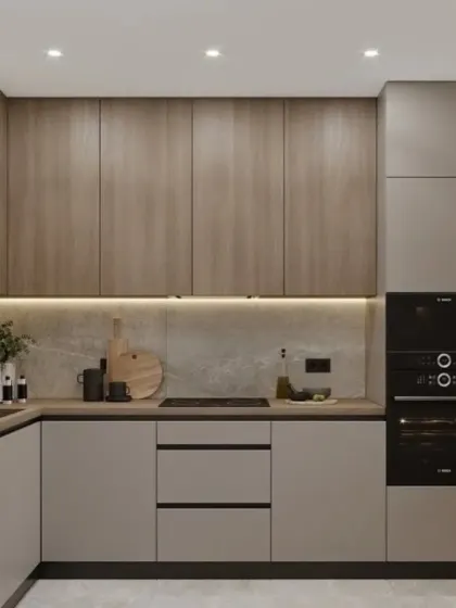 This compact kitchen design uses a mix of grey and wood-finish cabinets for a contemporary look. We integrated the oven and microwave at eye level for ergonomic convenience, demonstrating our focus on practical space planning.