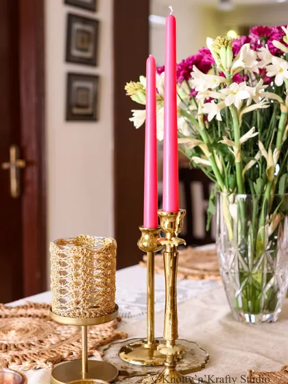 A close-up of the brass candle holders and a crochet-covered votive, adding texture and shine to the Diwali table.