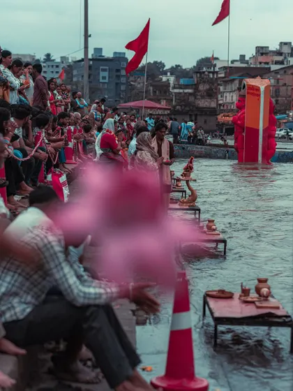 A motion-blur shot of the Ganga ghat during a festival, with a pink flower in the foreground. This technique conveys the movement and vibrant energy of the crowd.