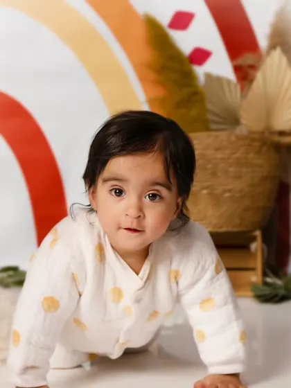 A close-up of a baby crawling towards the camera in our warm, earthy-toned boho rainbow setup.