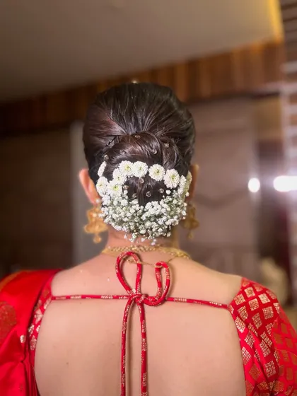 A closer look at the modern floral bun, featuring a clean, sleek finish with a crown of baby's breath. This style is perfect for securing a dupatta.