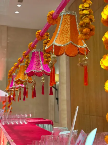 The bar area was decorated with hanging fabric lampshades in bright pink and orange, adorned with tassels and marigold strings. This creative decor element tied the bar into the overall festive theme.