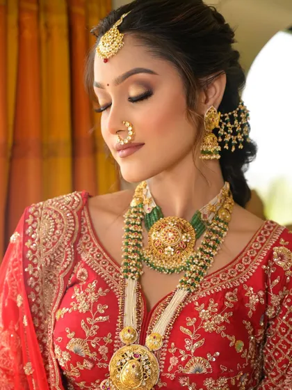 This look features a beautiful braided hairstyle adorned with traditional accessories. The eye makeup is a soft, golden-brown smokey eye, which adds depth while keeping the overall look classic and elegant.