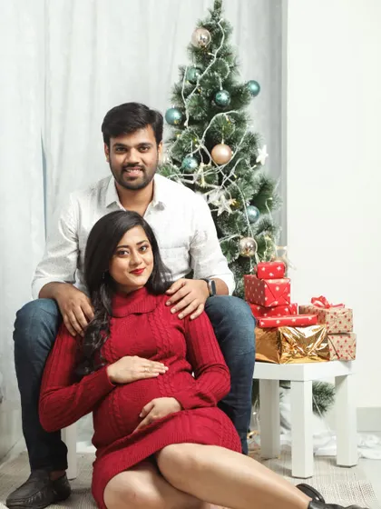 A festive holiday-themed maternity portrait. This couple celebrates their joy next to a Christmas tree, making for a warm and memorable seasonal photo.