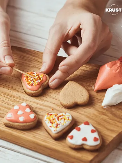A participant carefully decorating heart-shaped cookies with pink icing and sprinkles. It's a perfect shot of the creative process in our workshops.