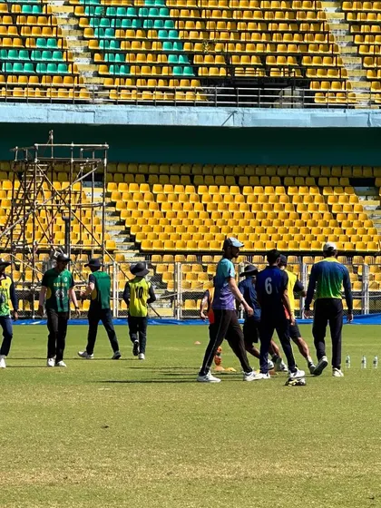 Players in a huddle during a fielding session. Team strategy and communication in action.